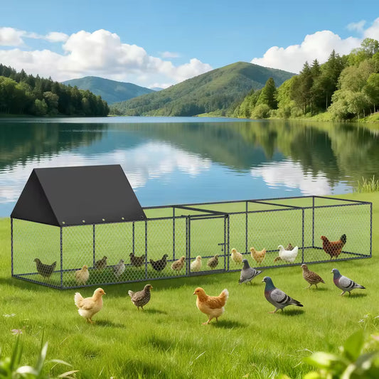 A metal wire chicken coop with a black roof sitting on a grassy shore by a scenic lake with mountains.