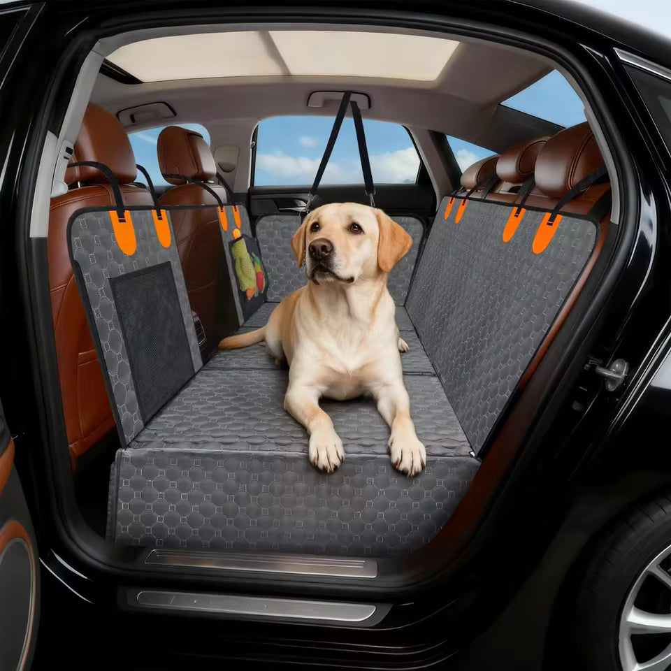 A yellow Labrador resting comfortably on a grey quilted car seat extender with side flaps in a car.