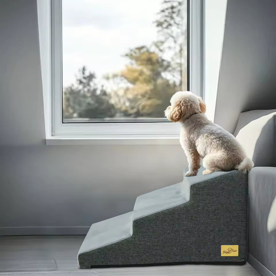 A small dog sits on top of a 4-step grey pet stair looking out a window.