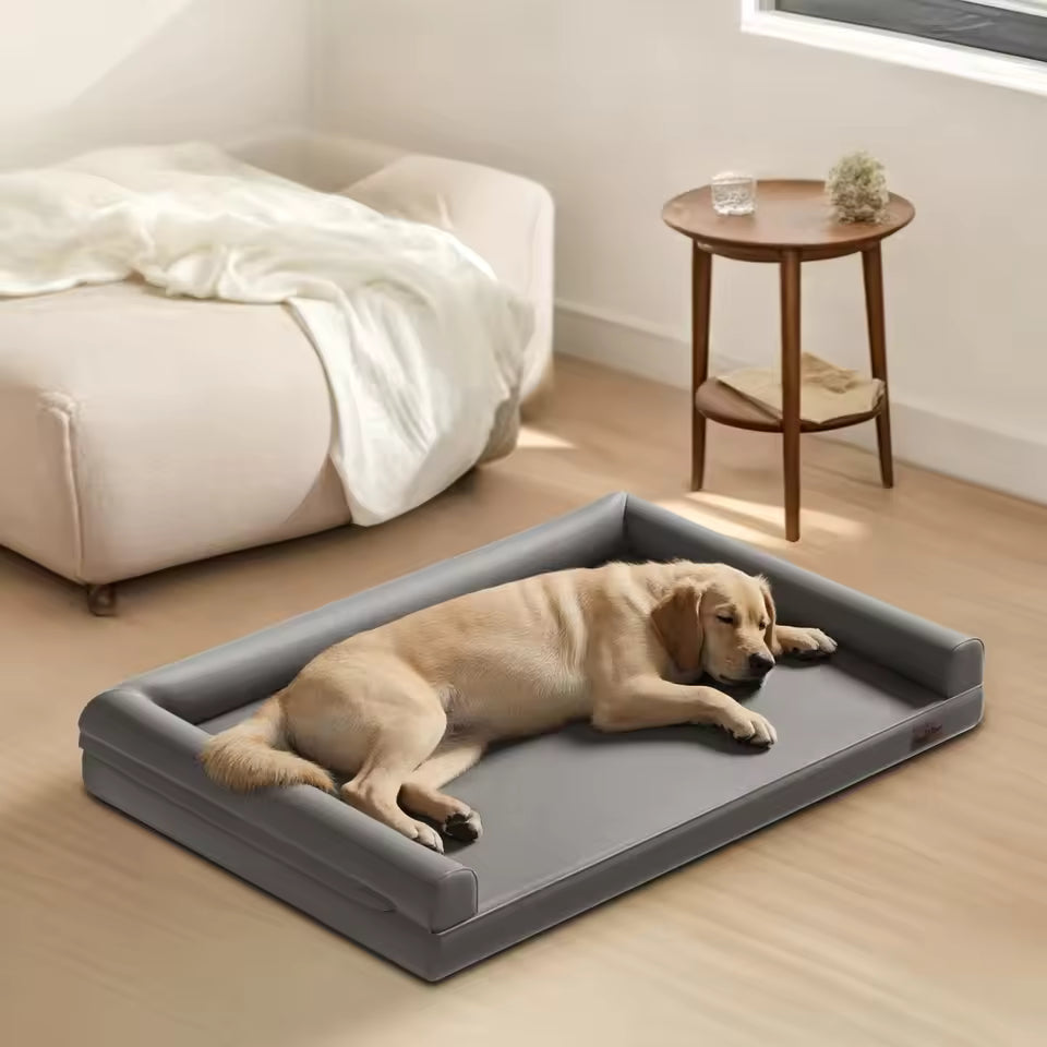 A golden retriever sleeping soundly on a grey leather bolster dog bed in a cozy room.