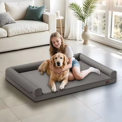 A young girl hugs her golden retriever on a large grey dog bed in a bright, modern living room.