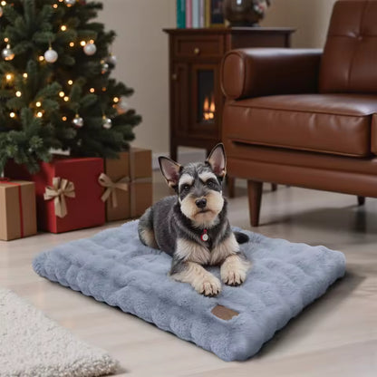 A fluffy grey dog bed with a small dog lying on it near a lit Christmas tree and presents.