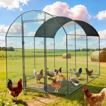 Large metal chicken coop with a dark cover, wire mesh walls, and poultry roaming inside and around it.