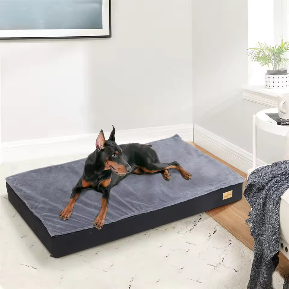 A Doberman resting on a large grey pet bed indoors.