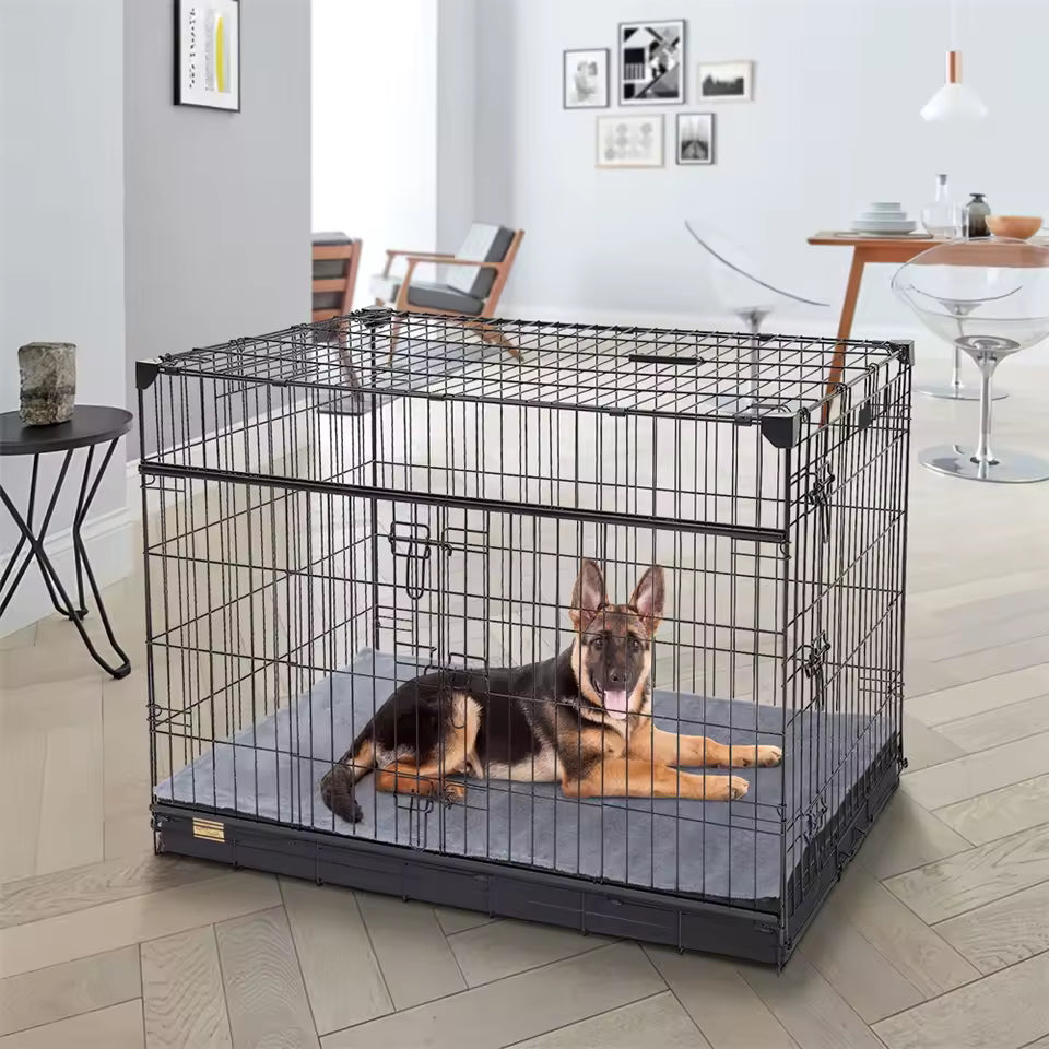 A German Shepherd resting inside a large black wire dog crate on a grey mat.