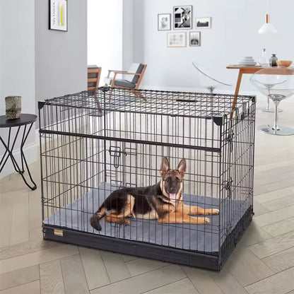 A German Shepherd resting inside a large black wire dog crate on a grey mat.
