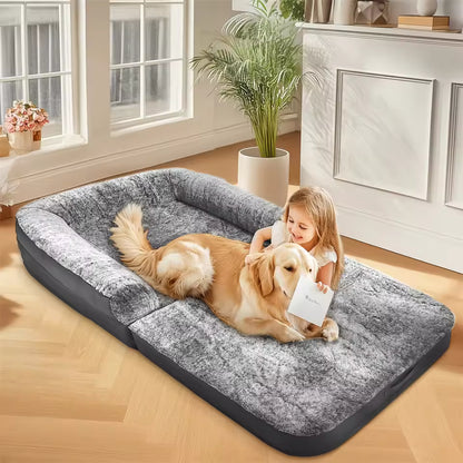 A young girl plays with a golden retriever on a large gray human-sized pet bed in a bright room.
