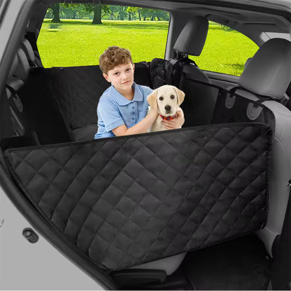 A young boy holds a puppy on a black quilted pet seat cover inside a car's back seat.