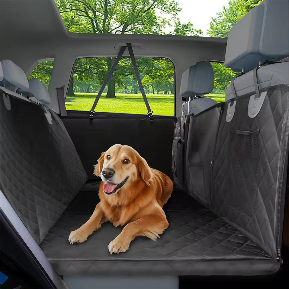 A golden retriever relaxes on a black quilted pet car seat cover in the back seat.