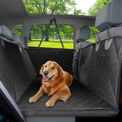 A golden retriever relaxes on a black quilted pet car seat cover in the back seat.